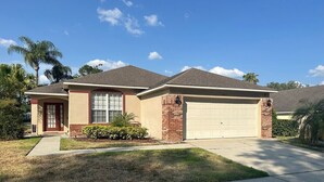 A single-story house with a garage, a front lawn, and a clear sky. - Beautiful Golf Course Views - Southern Dunes Villa (Haines City)