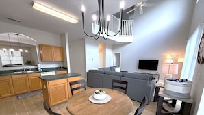 A modern kitchen with wooden cabinets, a dining table with chairs, a built-in oven, and a ceiling fan. - Plenty of Sunshine, Southern Dunes Pool Home (Haines City)