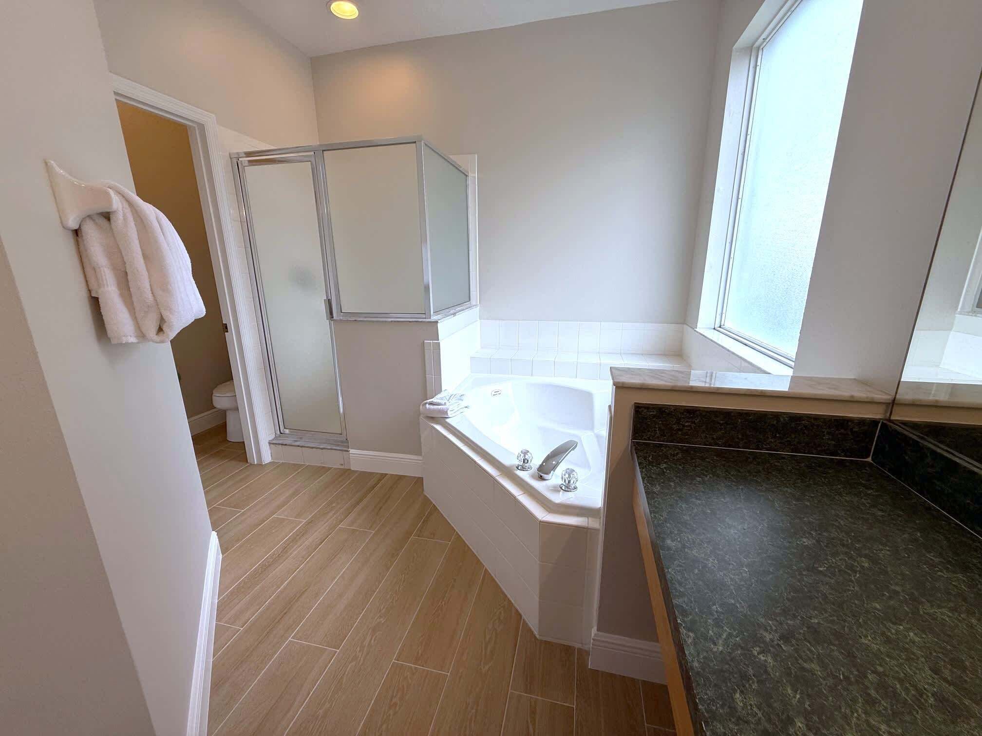 Une salle de bain moderne avec une douche, une baignoire et une grande fenêtre.