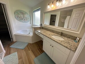 A bathroom with a bathtub, sink, vanity, and a large mirror. - Updated Pool Villa - Southern Dunes (Haines City)