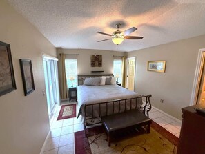 A bedroom with a bed, a ceiling fan, a bench, and a door. - Updated Golf Course View Villa - Southern Dunes (Haines City)