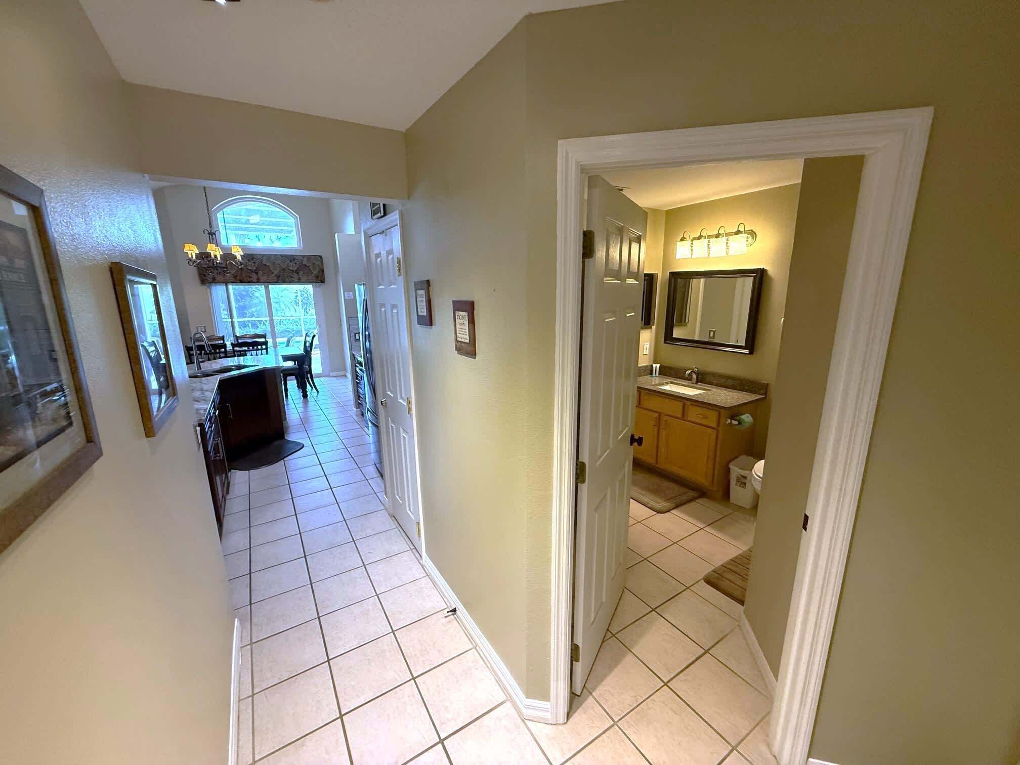A hallway with a dining area, a kitchen, and a bathroom.