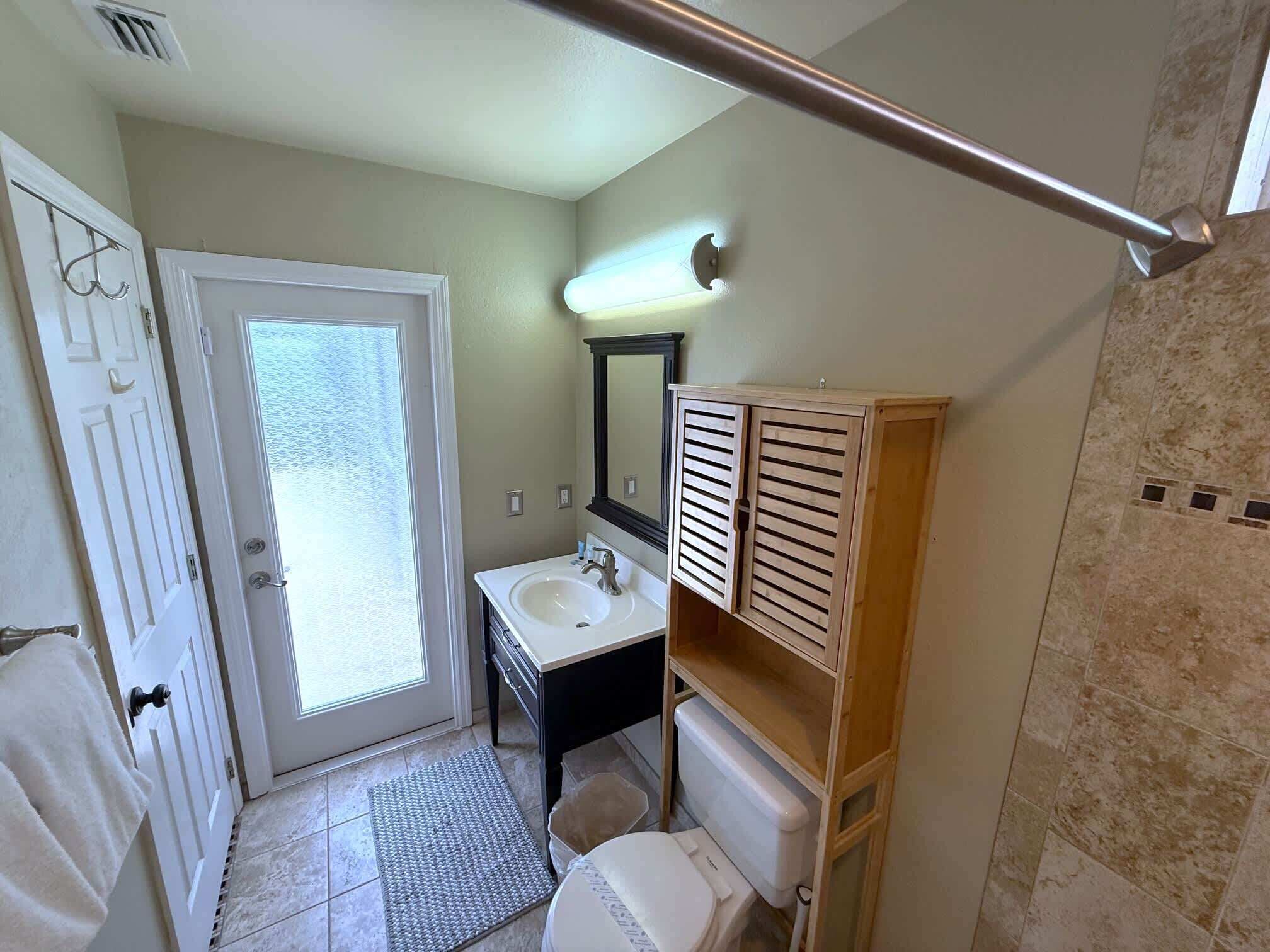A bathroom with a white door, a sink, a mirror, and a toilet.