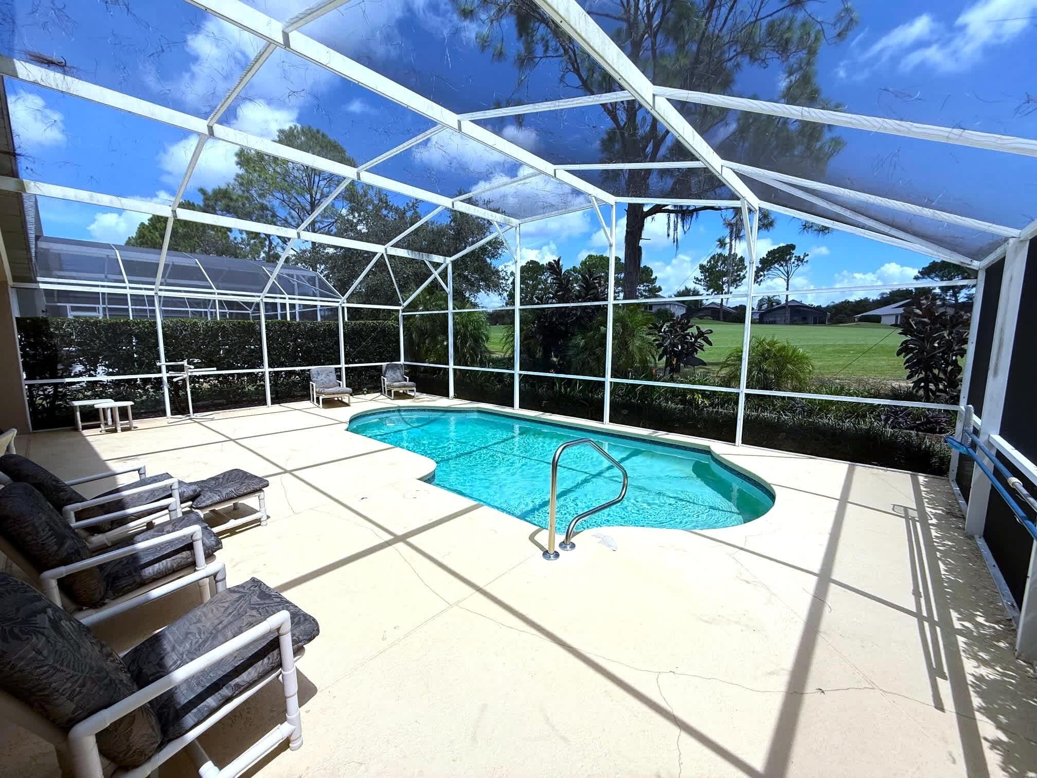 A covered swimming pool with lounge chairs and a view of the surrounding landscape.