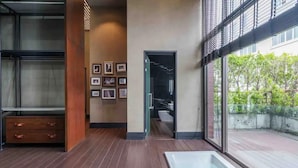 Une salle de bain moderne avec une grande baignoire, un plancher en bois et des tableaux encadrés accrochés au mur.