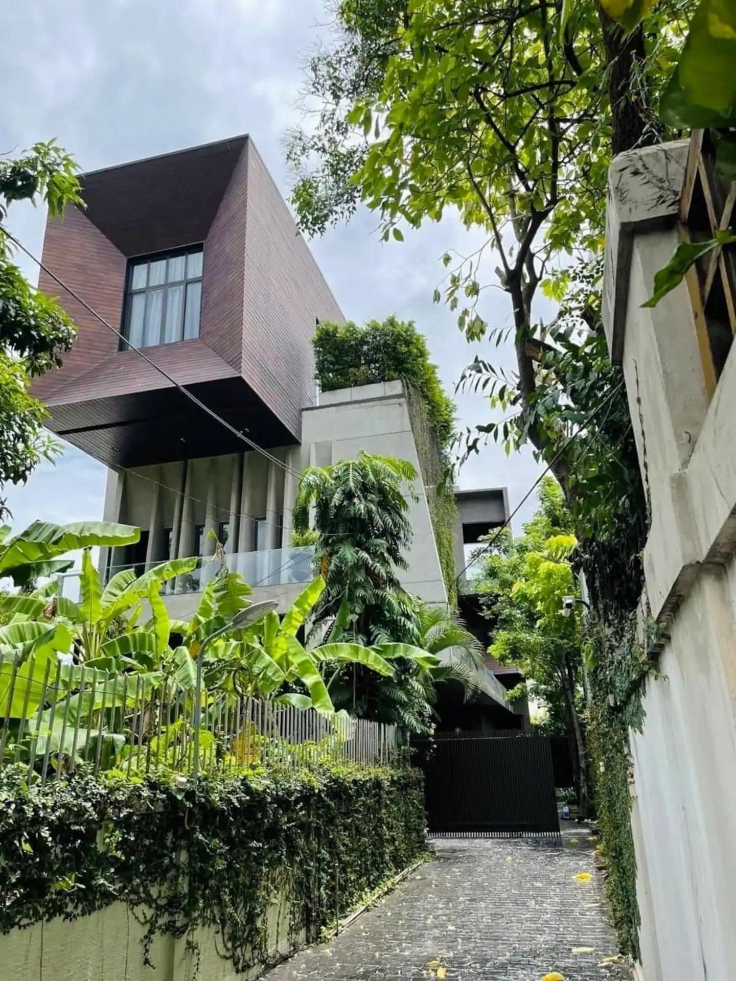 Ein modernes Gebäude mit einem einzigartigen geometrischen Design, umgeben von üppigem Grün und einem gepflasterten Weg.