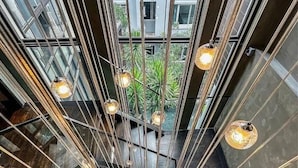 Un intérieur moderne avec un escalier central, des rampes en métal et des luminaires suspendus.