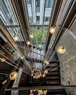 A modern interior with a central light fixture and a view of greenery outside. - The Oasis Tranquil Escape (Bangkok)