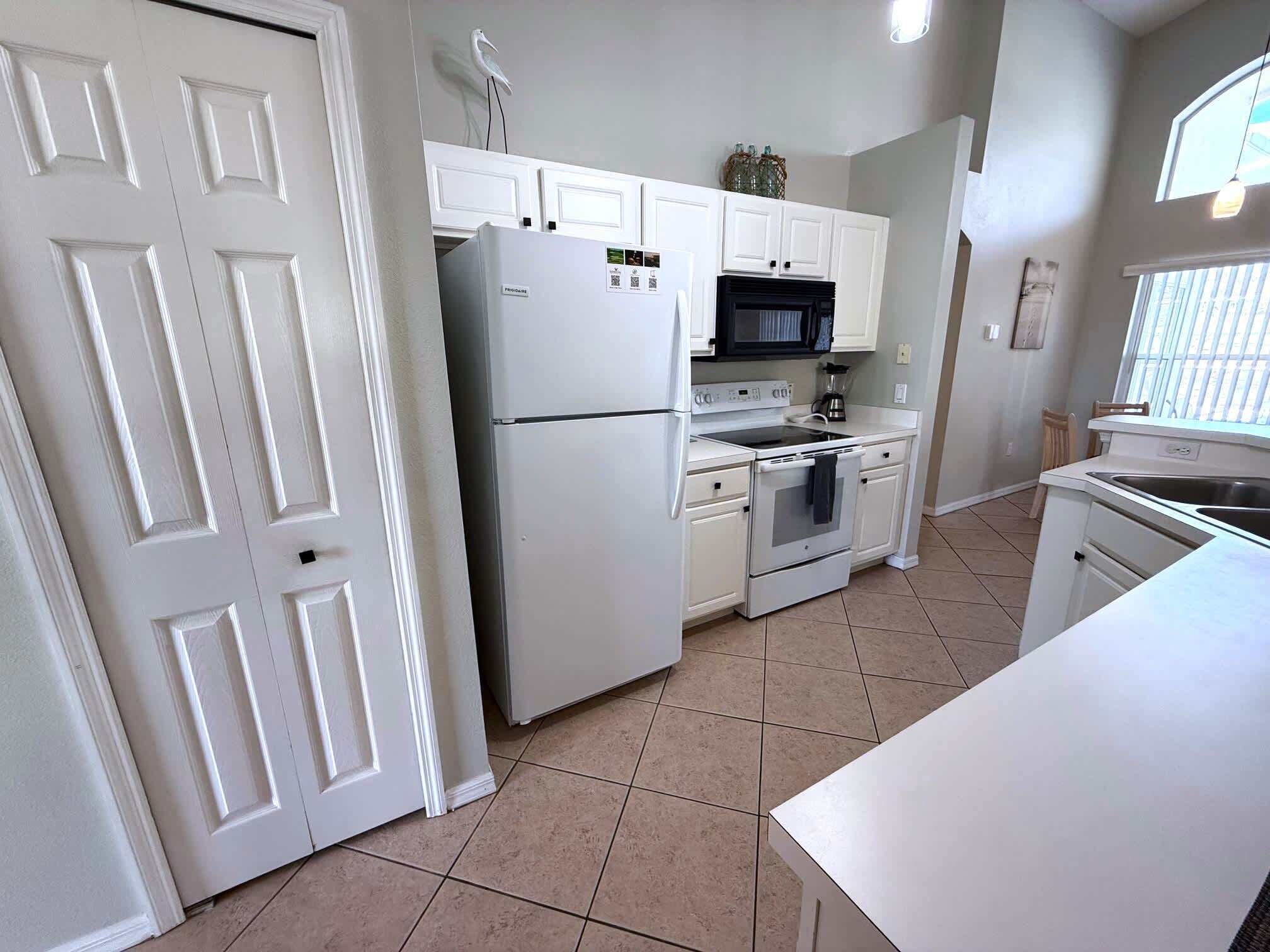 Una cocina con armarios blancos, un refrigerador, una estufa y un microondas.