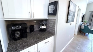 Eine moderne Küche mit weißen Schränken, einer Granitabdeckung und einer Kaffeemaschine.