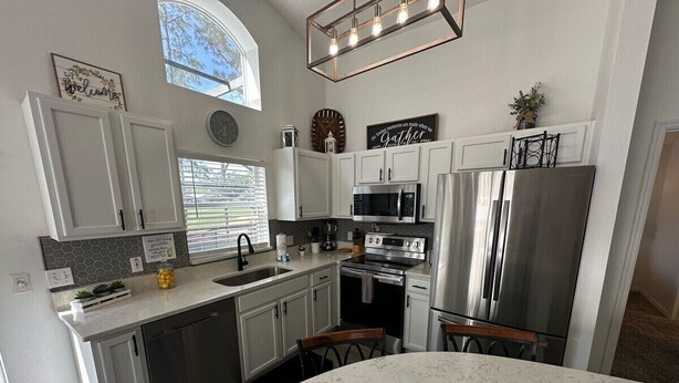 A modern kitchen with white cabinets, stainless steel appliances, and a large island. - South Facing Pool Villa, Golf Course Views, Southern Dunes (Haines City)