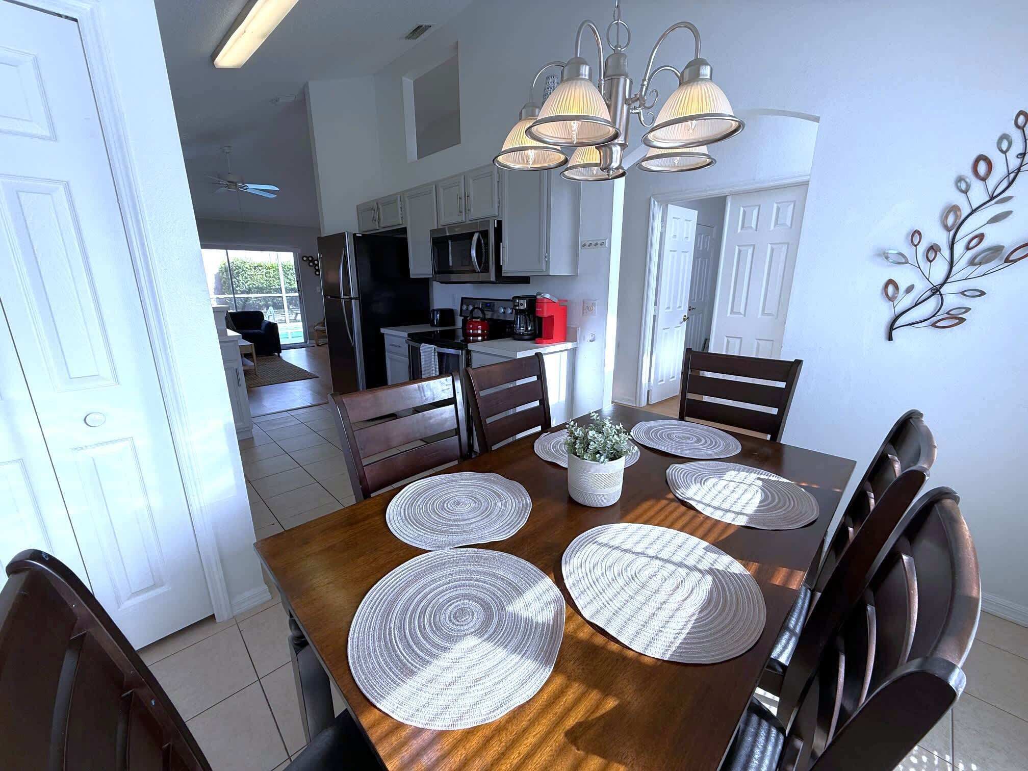 A dining area with a wooden table, four chairs, and a chandelier.