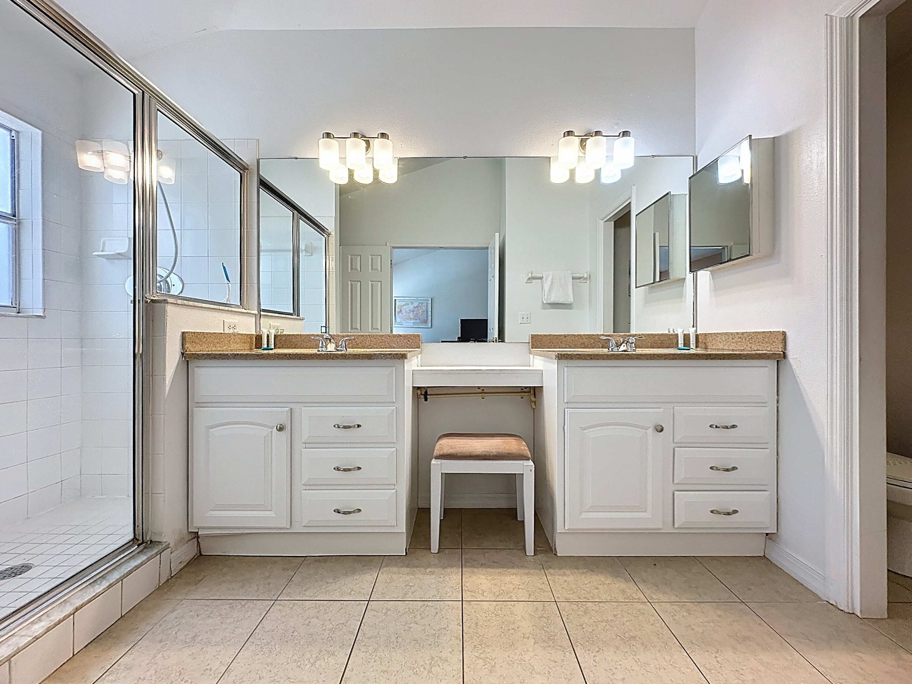 A bathroom with two sinks, a mirror above each, and a bench in the center.