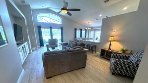 A spacious living room with a large sofa, patterned armchairs, a dining area with a table and chairs, and a ceiling fan. - Fully Remodeled Golf View Villa, Southern Dunes (Haines City)