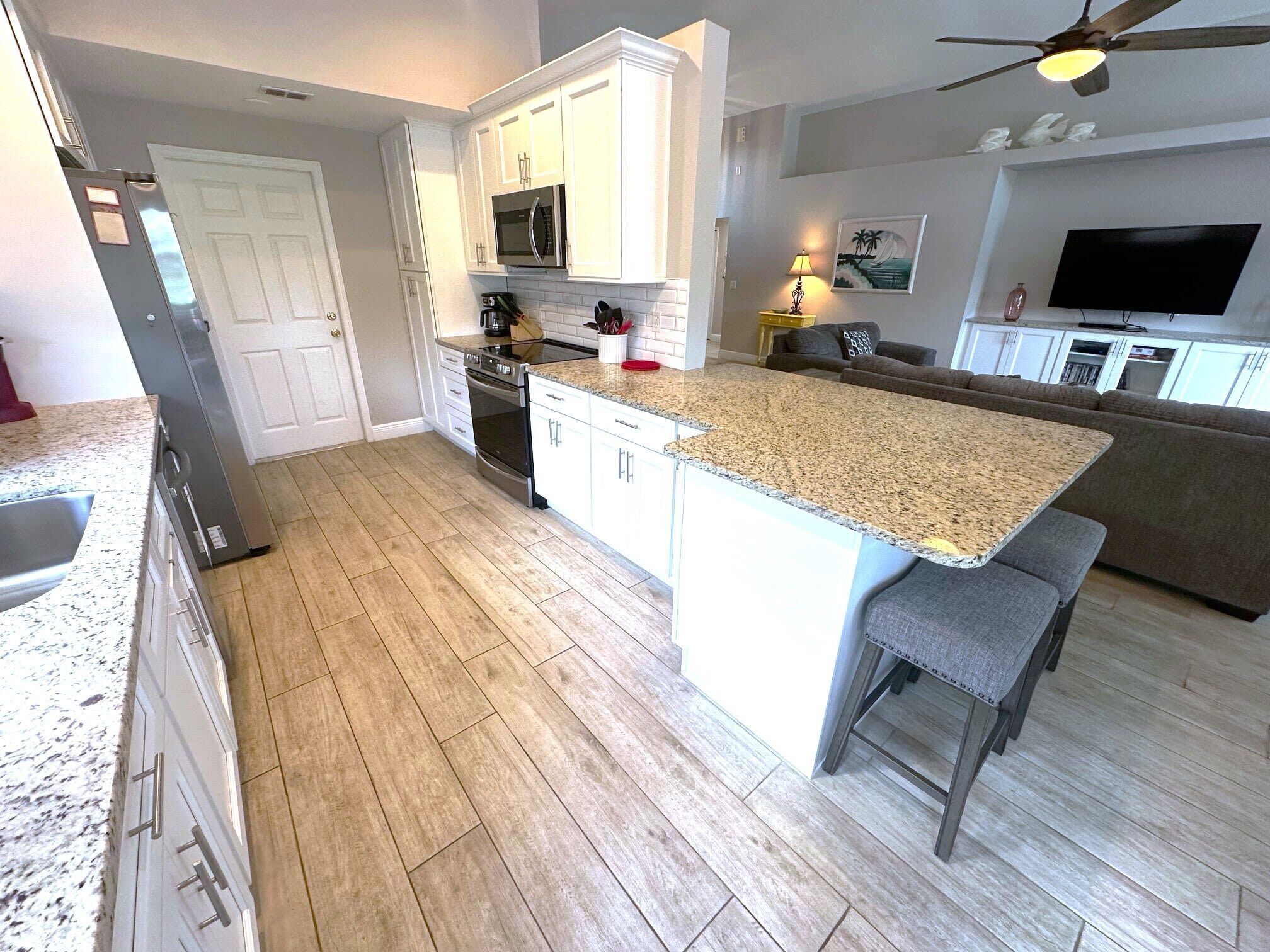 A modern kitchen with white cabinetry, a granite countertop, and a built-in oven.