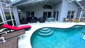 A covered outdoor swimming pool area with lounge chairs, a table, and a seating area. - Fully Remodeled Golf View Villa, Southern Dunes (Haines City)