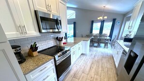 A modern kitchen with white cabinets, a stainless steel microwave, a gas stove, and a built-in oven. - Fully Remodeled Golf View Villa, Southern Dunes (Haines City)