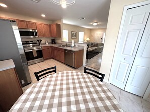 A modern kitchen with stainless steel appliances, wooden cabinets, and a checkered tablecloth. - Stunning Villa With Golf Course Views (Haines City)