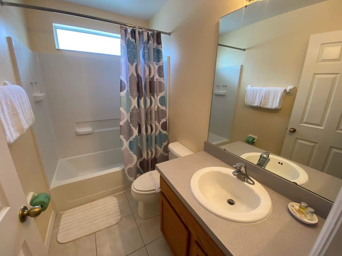 A bathroom with a bathtub, toilet, and two sinks with mirrors.