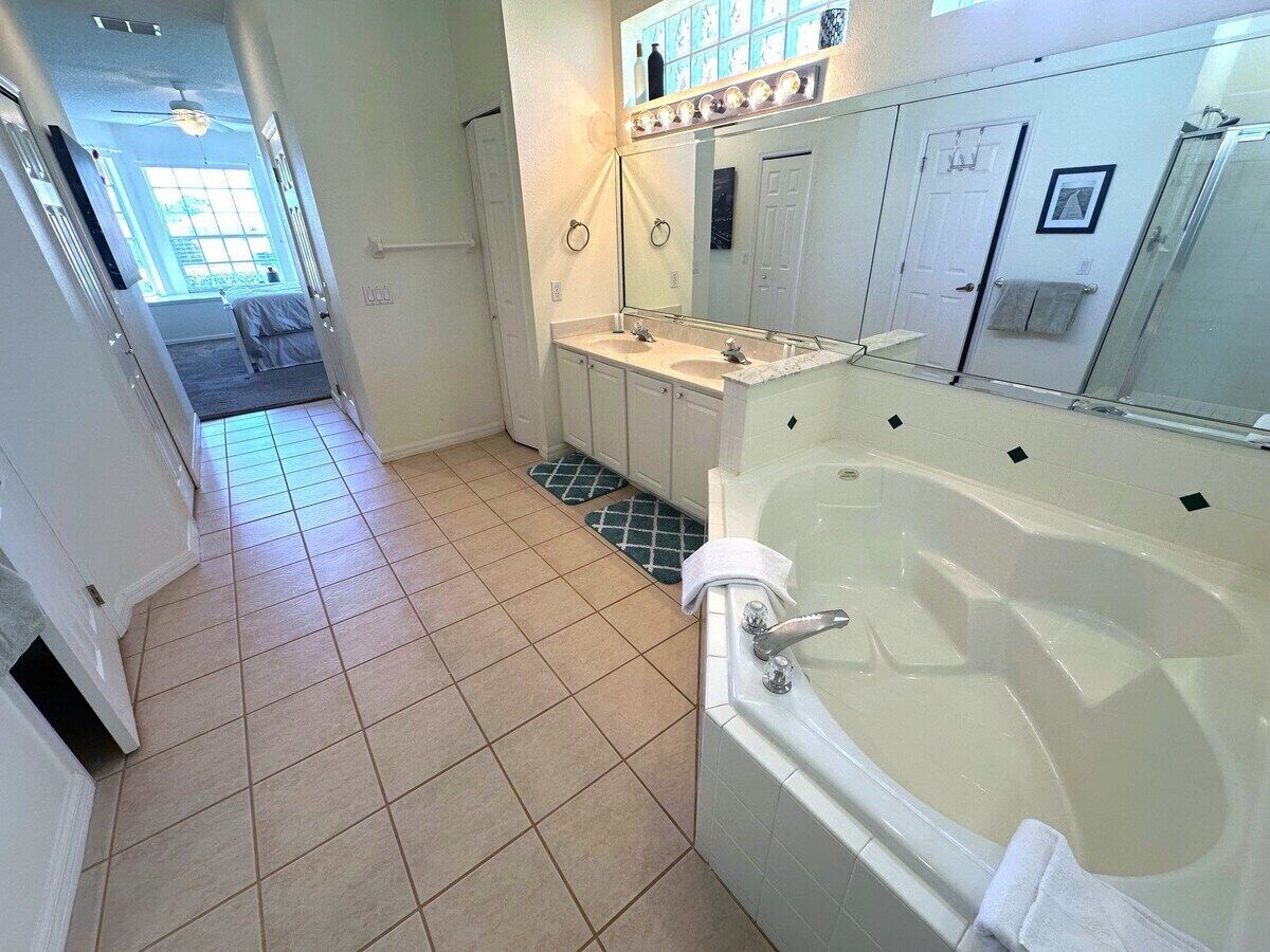 A bathroom with a bathtub, a vanity with a mirror, and a shower area.