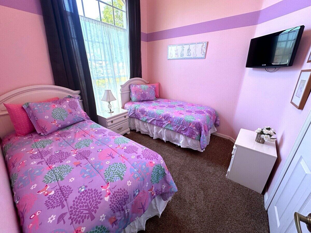 A bedroom with two beds, a television, and a small cabinet.