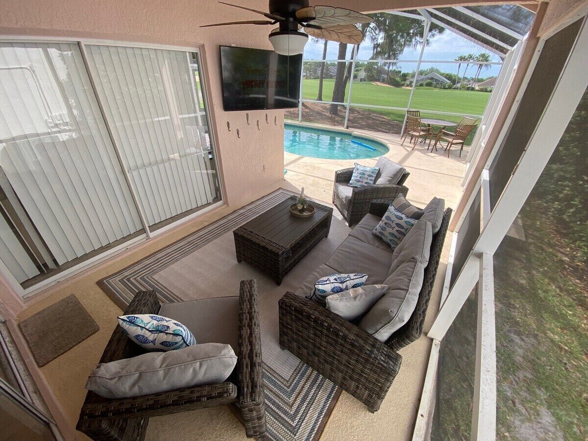 Un patio couvert avec une piscine, du mobilier d’extérieur et un ventilateur de plafond.