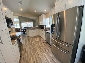 Una cocina moderna con armarios blancos, electrodomésticos de acero inoxidable y suelo de madera.