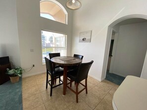 A dining area with a round table, black chairs, and a potted plant. - Southern Dunes - South Facing Villa (Haines City)
