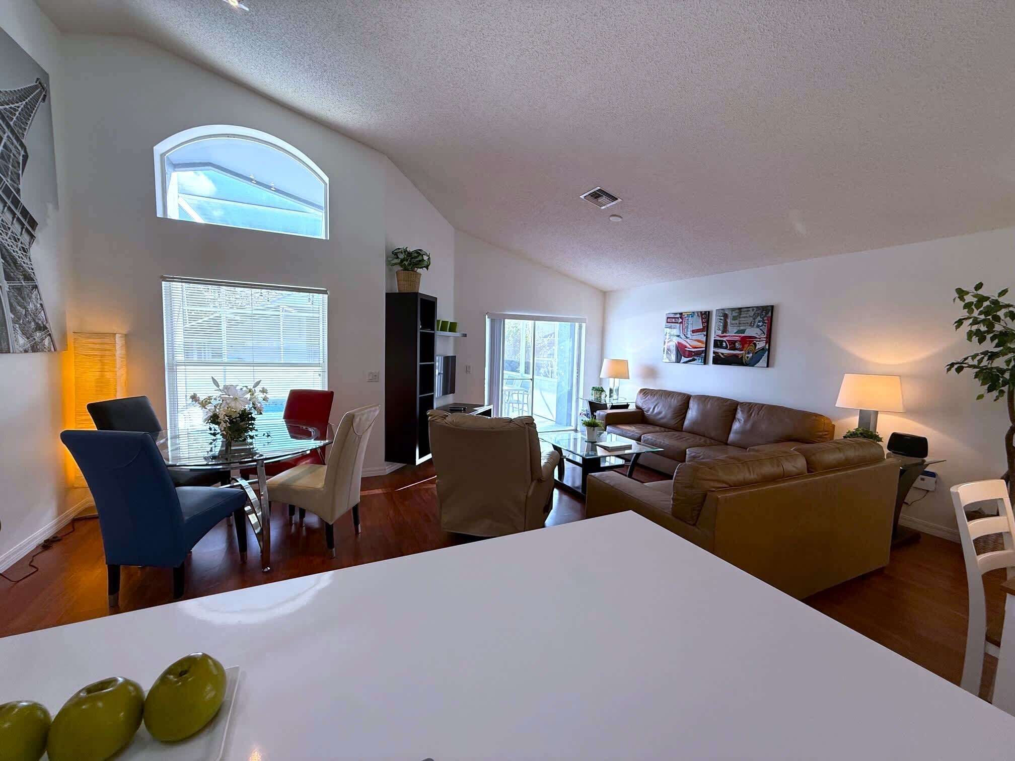 A spacious living area with a dining table, chairs, a sofa, and a TV.