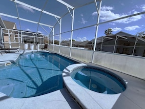 An indoor swimming pool with a clear view of the sky and neighboring houses. - South Facing Villa - Modern Finishes (Haines City)