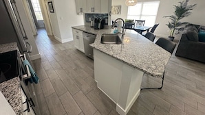 A modern kitchen with granite countertops, white cabinetry, and a central island. - Updated Pool Villa, Southern Dunes (Haines City)