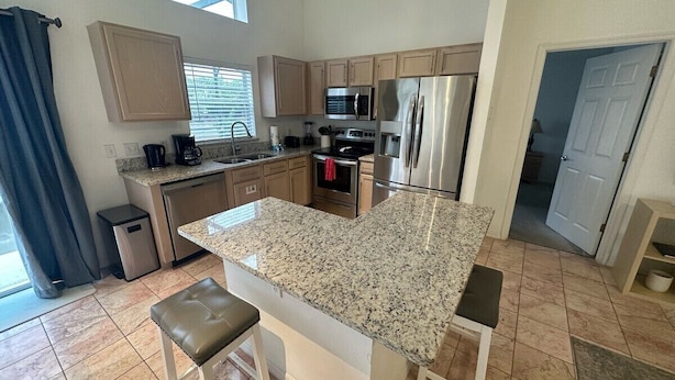 A modern kitchen with granite countertops, stainless steel appliances, and a central island with seating. - Golf Front Villa With Upgrades! (Haines City)