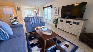 Ein Wohnzimmer mit Sofa, Couchtisch, Fernseher und Schrank.