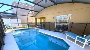 Ein Schwimmbad mit Glasüberdachung, umgeben von Liegestühlen und einer überdachten Terrasse.