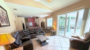 A spacious living room with a sectional sofa, a coffee table, and a dining area with chairs. - Golf Course Views, Large Pool Deck Villa in Southern Dunes (Haines City)