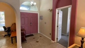 A spacious entryway with a tiled floor, a dining area with a table and chairs, and a large arched doorway. - Golf Course Views, Large Pool Deck Villa in Southern Dunes (Haines City)