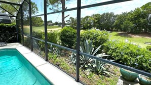 Una piscina con vista a un jardín ajardinado y un campo de golf.