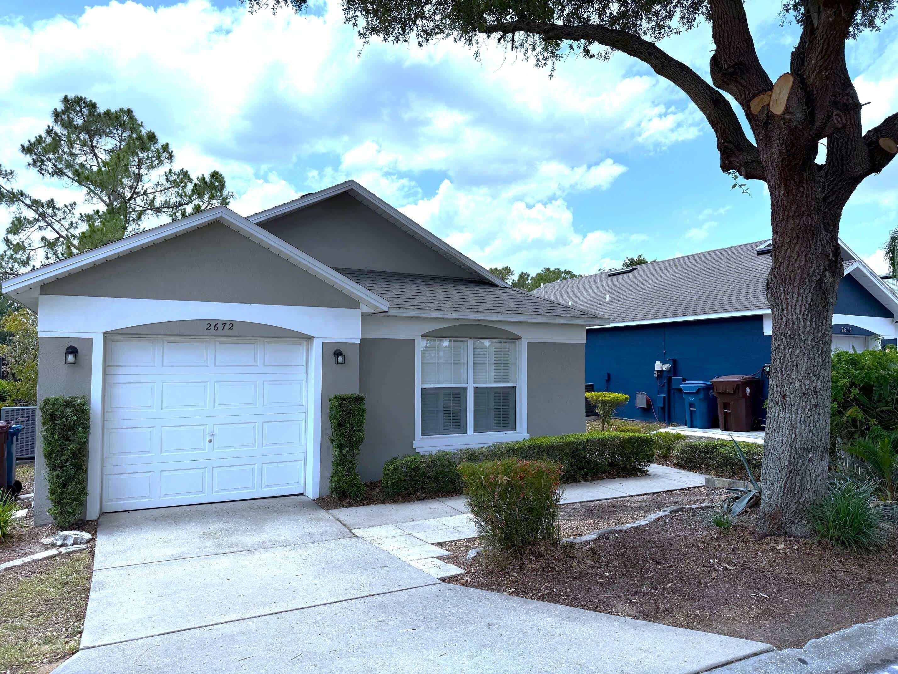 A residential house with a garage, a small front yard, and a tree.