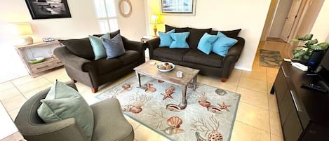 A living room with two sofas, a coffee table, and a patterned rug.