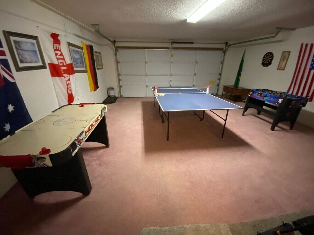 A room with two foosball tables, a pool table, and a dartboard.
