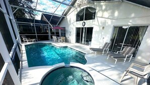 Ein Swimmingpool mit Whirlpool, Liegestühlen und einer überdachten Terrasse.