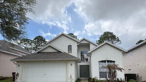 A two-story house with a garage, a front door, and a small front yard with landscaping. - 8th Fairway Pool Villa, Southern Dunes (Haines City)