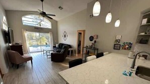 A modern kitchen with a large island, wooden flooring, and pendant lighting. - Remodeld South Facing Villa - Southern Dunes Golf Course Views (Haines City)