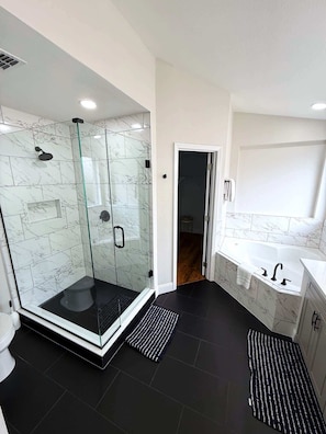 A modern bathroom with a glass-enclosed shower, a freestanding bathtub, and a large mirror above the sink. - Remodeld South Facing Villa - Southern Dunes Golf Course Views (Haines City)