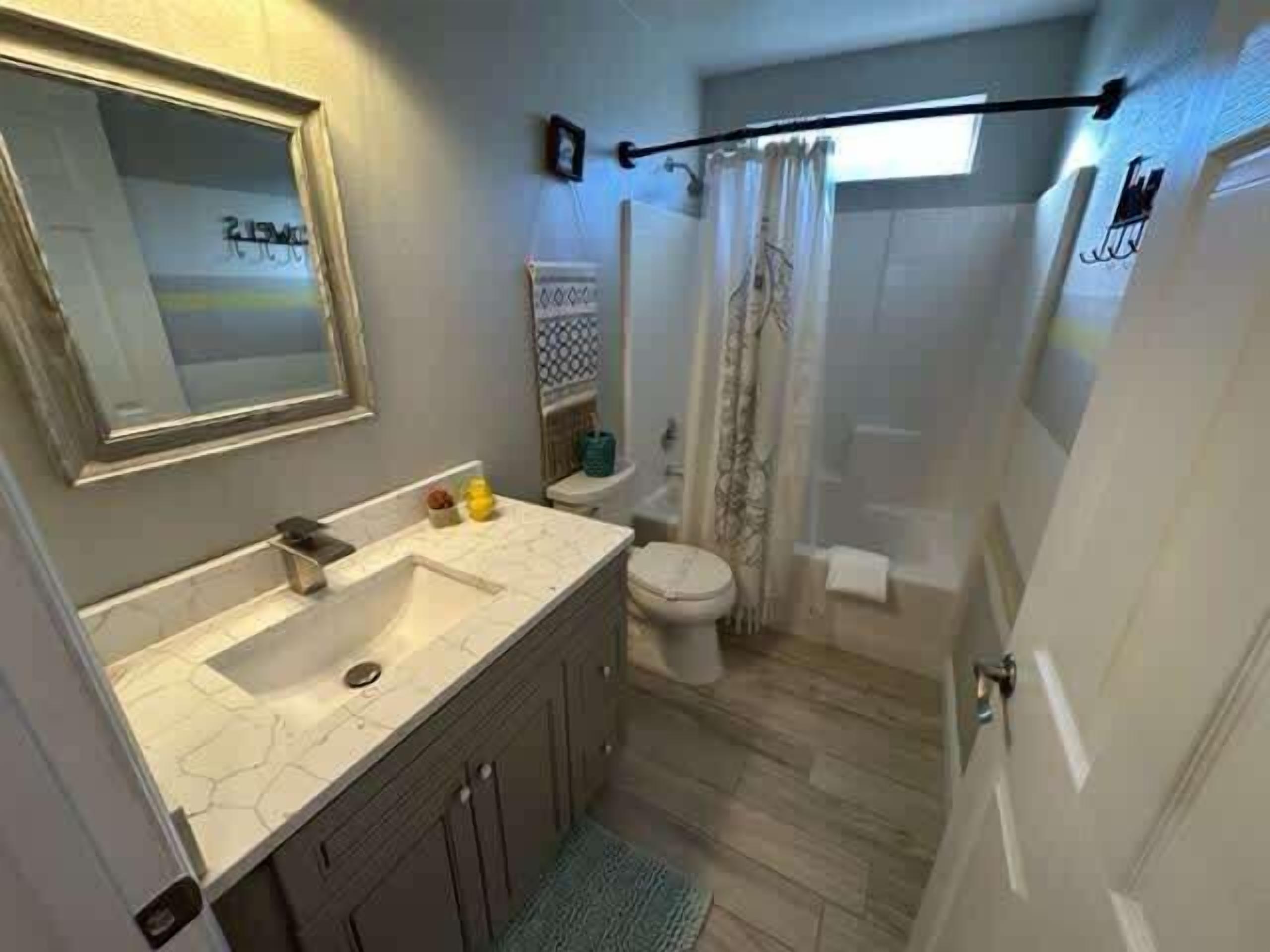 A bathroom with a sink, toilet, and shower area.