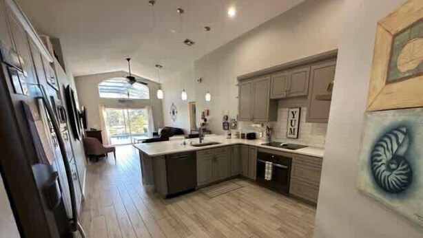 A spacious kitchen with wooden flooring, a large island, and pendant lighting. - Remodeld South Facing Villa - Southern Dunes Golf Course Views (Haines City)