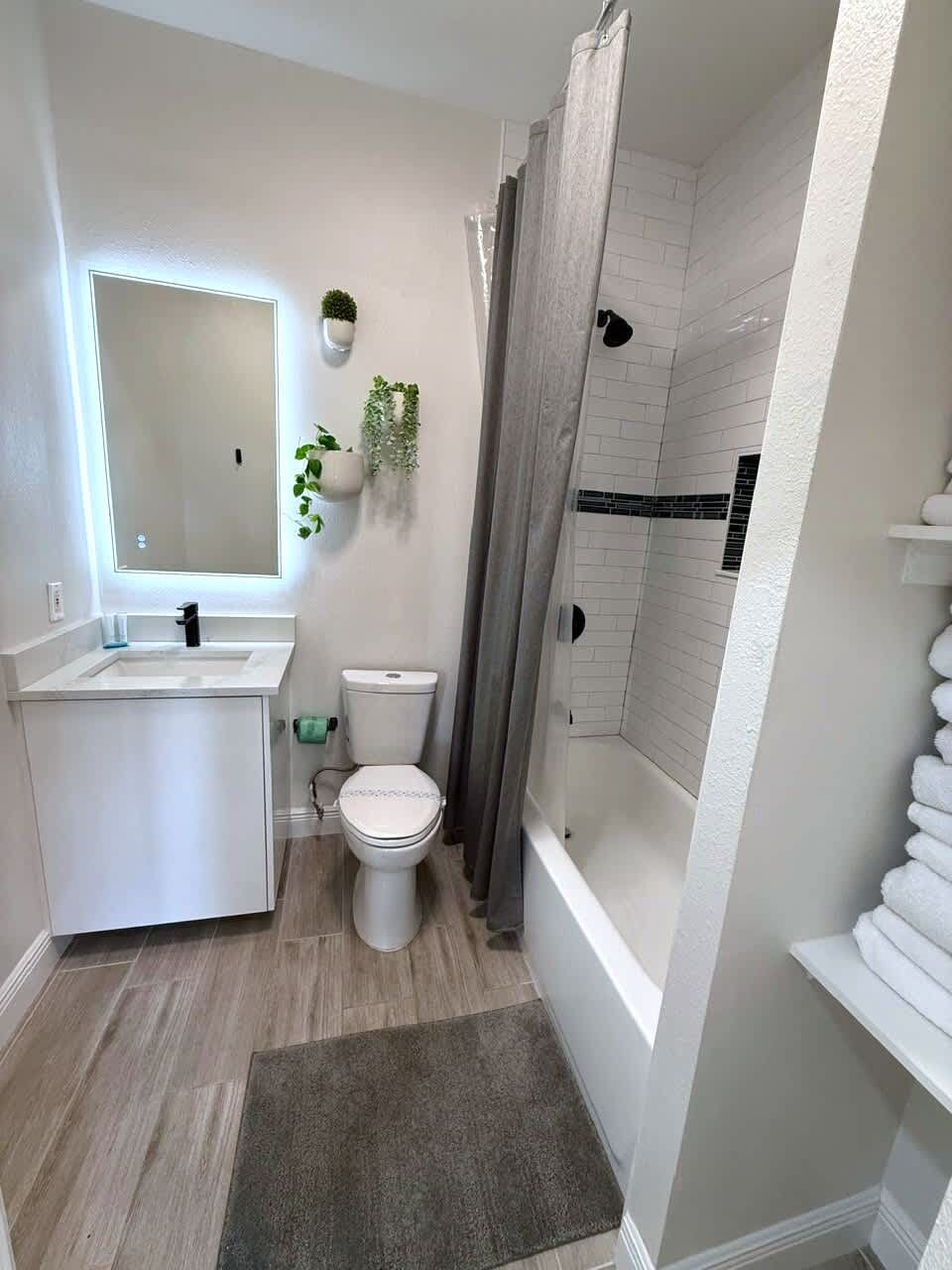 Een moderne badkamer met douche, toilet en wastafel.