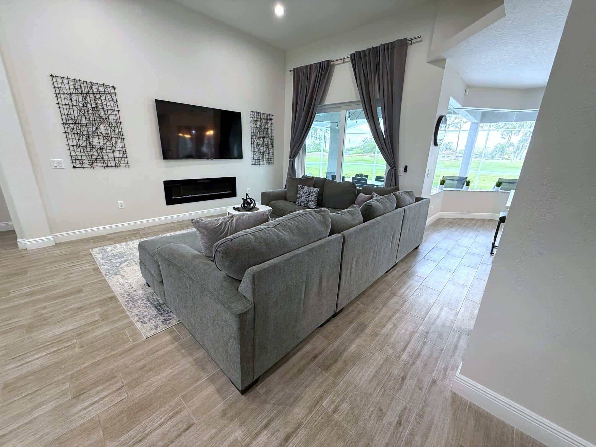 A modern living room with a sectional sofa, a flat-screen TV, and a fireplace.