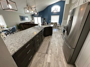 A modern kitchen with dark cabinetry, granite countertops, and a stainless steel refrigerator. - Fully Updated Holiday Villa, Southern Dunes, South Facing Pool (Haines City)