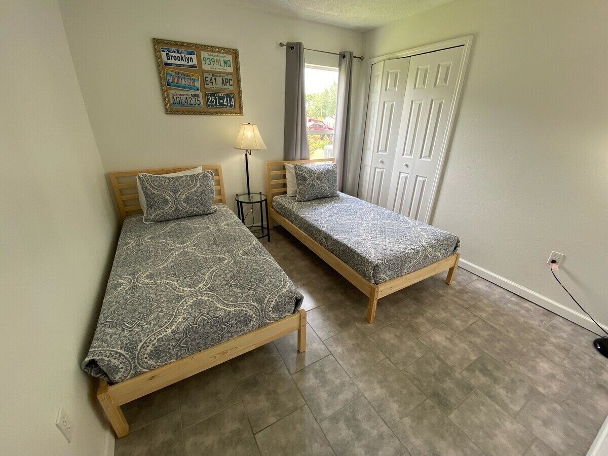 A room with two beds, a lamp, a door, and a wall-mounted sign.